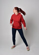 © faestock - full length figure of female model wearing  basic contemporary casual clothing, red hoodie jumper, skinny jeans, sneakers. walking action pose, isolated white studio background.