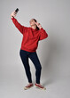 © faestock - full length figure of female model wearing  basic contemporary casual clothing, red hoodie jumper, skinny jeans, sneakers. standing walking pose holding cell phone mobile,  isolated white studio backg
