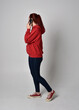 © faestock - full length figure of female model wearing  basic contemporary casual clothing, red hoodie jumper, skinny jeans, sneakers. standing walking pose holding cell phone mobile,  isolated white studio backg