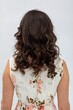 © fotodrobik - Studio shot of woman showcasing casual floral attire and relaxed demeanor, Portrait of female model with loose dark curls and timeless fashion style in bright studio setting