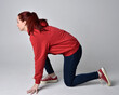 © faestock - full length figure of female model wearing  basic contemporary casual clothing, red hoodie jumper, skinny jeans, sneakers.  kneeling on floor  isolated white studio background.