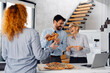 © Novak - Happy diverse business team enjoying a pizza lunch break together in a modern office.