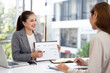© Fahng - Smiling asian analyst showing client or colleague annual financial report analyzing business data in meeting room.