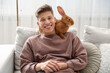 © New Africa - Happy man with cute bunny on sofa at home