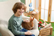 © New Africa - Little boy with cute Easter bunny in armchair indoors