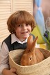 © New Africa - Little boy holding wicker basket with cute Easter bunny indoors, closeup