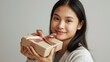 © LimeSky - A beautiful young Asian woman holding a wrapped gift alone