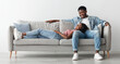 © Prostock-studio - Free Time Together. Happy beautiful African American couple spending weekend resting on couch indoors at home in living room, relaxing and enjoying the company of each other, woman lying on man's lap