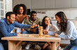 © Prostock-studio - A group of engaged multiracial friends participate in a tense wooden block tower game at a table, showing concentration and fun