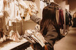 © Nataliya - A brunette girl chooses clothes for a newborn baby in the baby department.