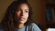 © Lifestyle Images - Close-up portrait of a young woman with curly hair. she is looking off to the side with a thoughtful expression on her face. she has a slight smile on her lips and is wearing a gray sweater.