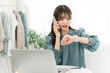 © buritora - A stylish young Asian woman using a computer while talking on her smartphone