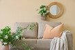 © Pixel-Shot - Interior of living room with sofa and blooming jasmine flowers near beige wall, closeup