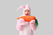 © Pixel-Shot - Funny senior woman in Easter bunny costume with plush carrot on white background
