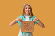 © Pixel-Shot - Happy young pin-up woman holding card with text GIRL POWER on yellow background