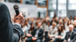 © Kanomaoi - Close up of hand holding microphone while moderating professional conference panel discussion