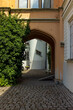 © Janiel Kaffe - Arched stone passage with cobblestone path and green ivy leading to a sunny castle courtyard