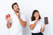 © luismolinero - Young couple holding chocolate and apple isolated on white background thinking an idea while looking up