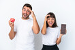 © luismolinero - Young couple holding chocolate and apple isolated on white background has just realized something and has intending the solution
