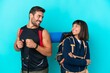 © luismolinero - Young mountaineer couple with a big backpack isolated on blue background looking over the shoulder with a smile