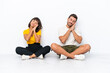 © luismolinero - Young couple sitting on the floor isolated on white background making sleep gesture in dorable expression