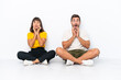 © luismolinero - Young couple sitting on the floor isolated on white background surprised and shocked while looking right