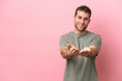 © luismolinero - Young caucasian man isolated on pink background holding copyspace imaginary on the palm to insert an ad