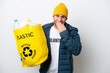 © luismolinero - Young caucasian holding a bag full of plastic bottles to recycle isolated on white background happy and smiling covering mouth with hand