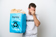 © luismolinero - Young caucasian man holding a recycling bag full of paper to recycle isolated on white background with tired and sick expression