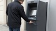 © fotogurme - Adult man in winter jacket using an outdoor ATM on a city street, close view of cash withdrawal, everyday banking and personal finance concept, holiday shopping season