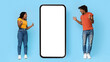 © Prostock-studio - Emotional african american millennials stylish man and woman looking at big smartphone with white black screen between them and gesturing, blue studio background, panorama, mockup