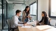 © Joseph - Group team of young man and business women discussing project sitting at table in office. Corporate workers people work together. Female woman mentor leader coach have meeting.
