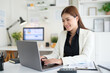 © wattana - Professional businesswoman working on a laptop at a modern office desk.