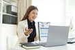© wattana - Professional accountant presenting financial charts during an online meeting, explaining business results using a laptop in a modern office.