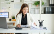 © wattana - Focused female accountant calculating numbers with a calculator beside a laptop and reports at a modern office.