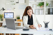 © wattana - Professional accountant reviewing financial reports on a clipboard while working at her desk.