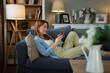 © Jelena - Woman relaxing on sofa, using mobile phone at home