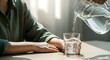 © MistoGraphy - Person pouring fresh water from a glass pitcher into a tumbler on a table indoors