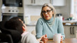© DMegias - Mother holding her adult son's hand, offering care and emotional support in a kitchen setting during a conversation