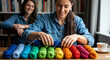 © Andrey - Woman organizing colorful yarn by shade while smiling indoors