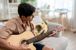 © Kawee - Asian handsome man musician playing an acoustic guitar in house.