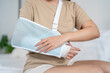 © Kawee - Close up of injured woman wearing splint on hand in bedroom at home.