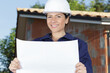 © auremar - smiling woman builder wearing protective helmet holds white sign board