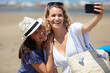 © auremar - smiling friends taking a selfie at the beach