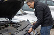 © Галя Дорожинська - A man positions the engine cover back onto the engine of a vehicle in a parking area