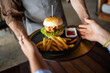 © NDABCREATIVITY - Casual dining lifestyle, waiter serves a delicious burger and fries in a relaxed restaurant setting