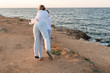 © svetograph - Couple Cliffside Ocean View - Two people in white clothing stand on a cliff overlooking the ocean at sunset.