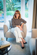 © gzorgz - Blond haired woman relaxing in an armchair in her modern home