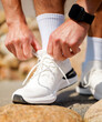 © muse studio - Person ties shoelaces on white running shoes during outdoor activity in a natural setting