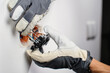 © Lazy_Bear - Electrician hands wearing protective gloves connecting exposed copper electrical wires to wall light switch. Concept of electrical safety, professional repair, home renovation and maintenance